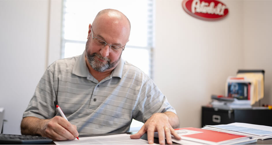 A Peterbilt employee works in an office creating finance documents for a customer